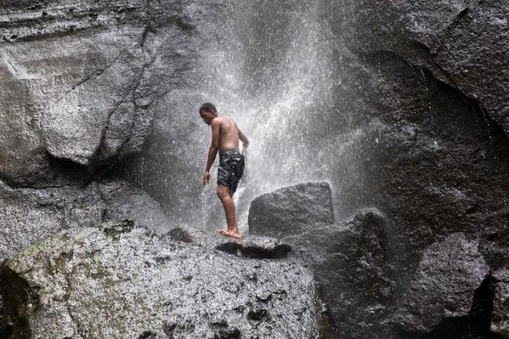 Man underneath a waterfall in the tropical rainforest
