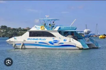 Boat named Flying Ray on water with a scenic background.